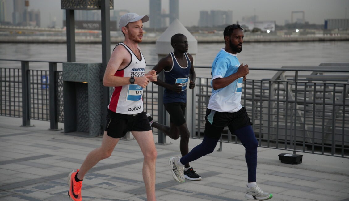 Three runners participating in a road race along Dubai's waterfront promenade