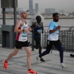Three runners participating in a road race along Dubai's waterfront promenade
