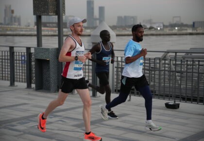 Three runners participating in a road race along Dubai's waterfront promenade