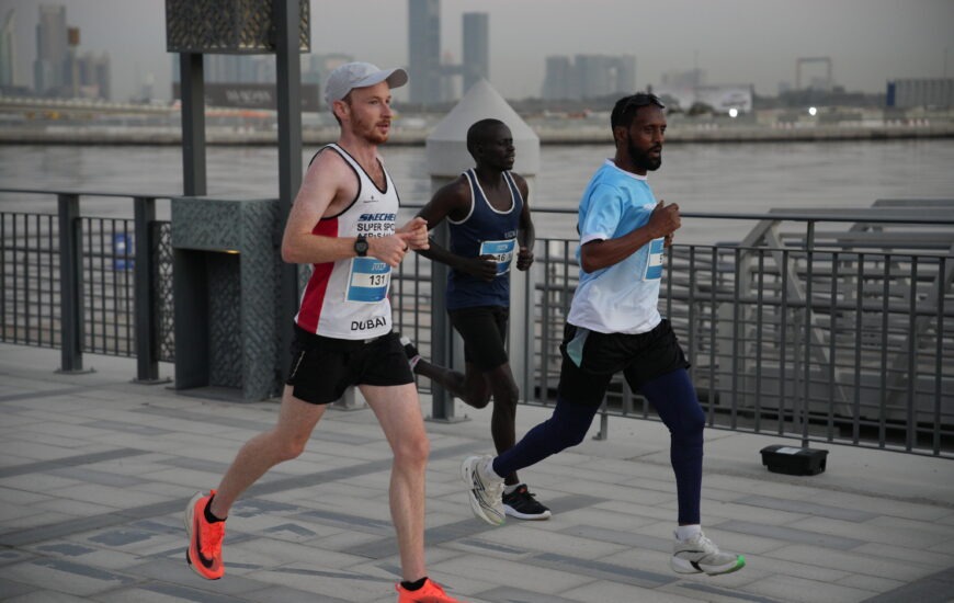 Three runners participating in a road race along Dubai's waterfront promenade