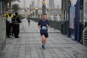 Runner participating in a road race on a Dubai city street.